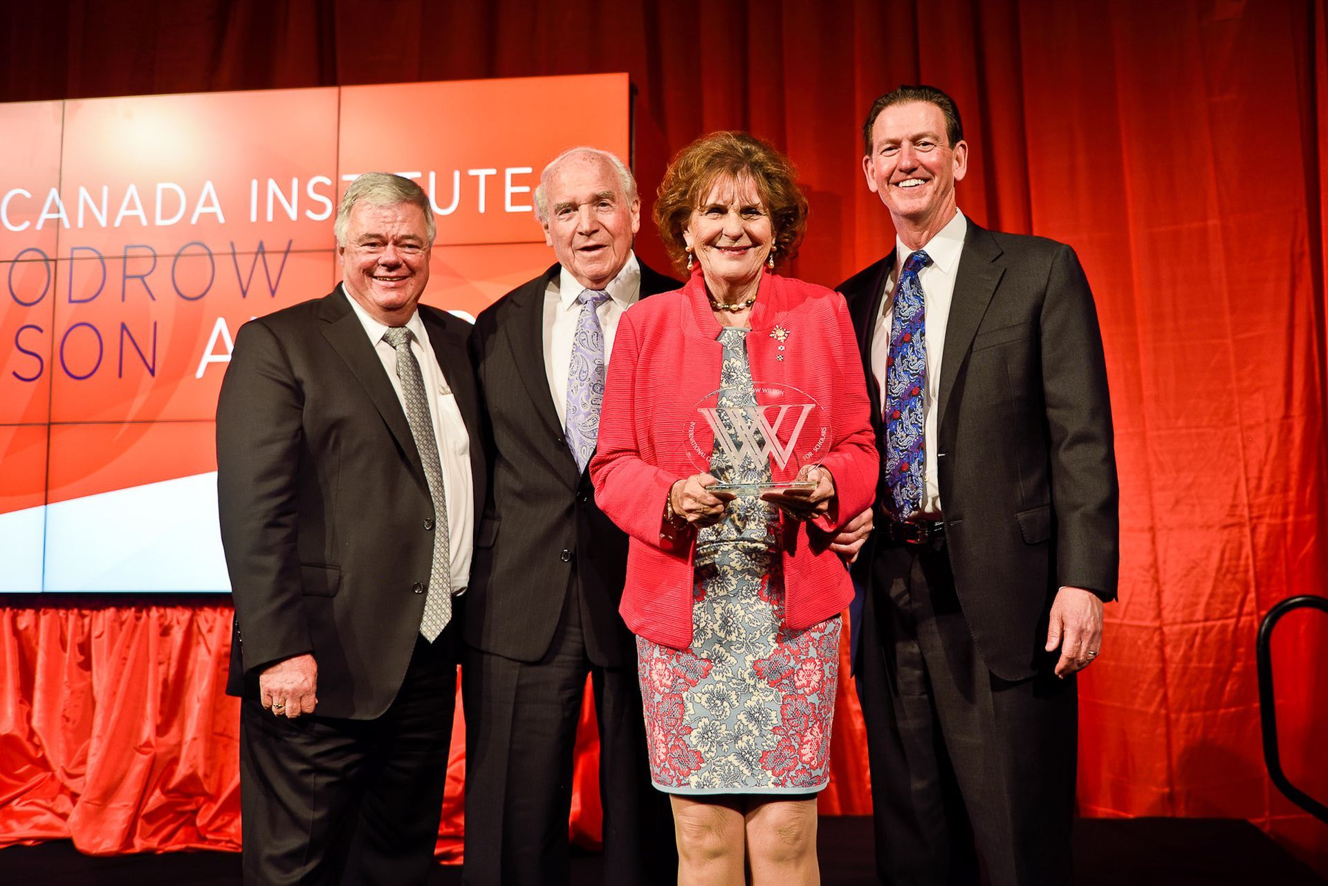 A group of men and a woman are posing for a picture on a stage.