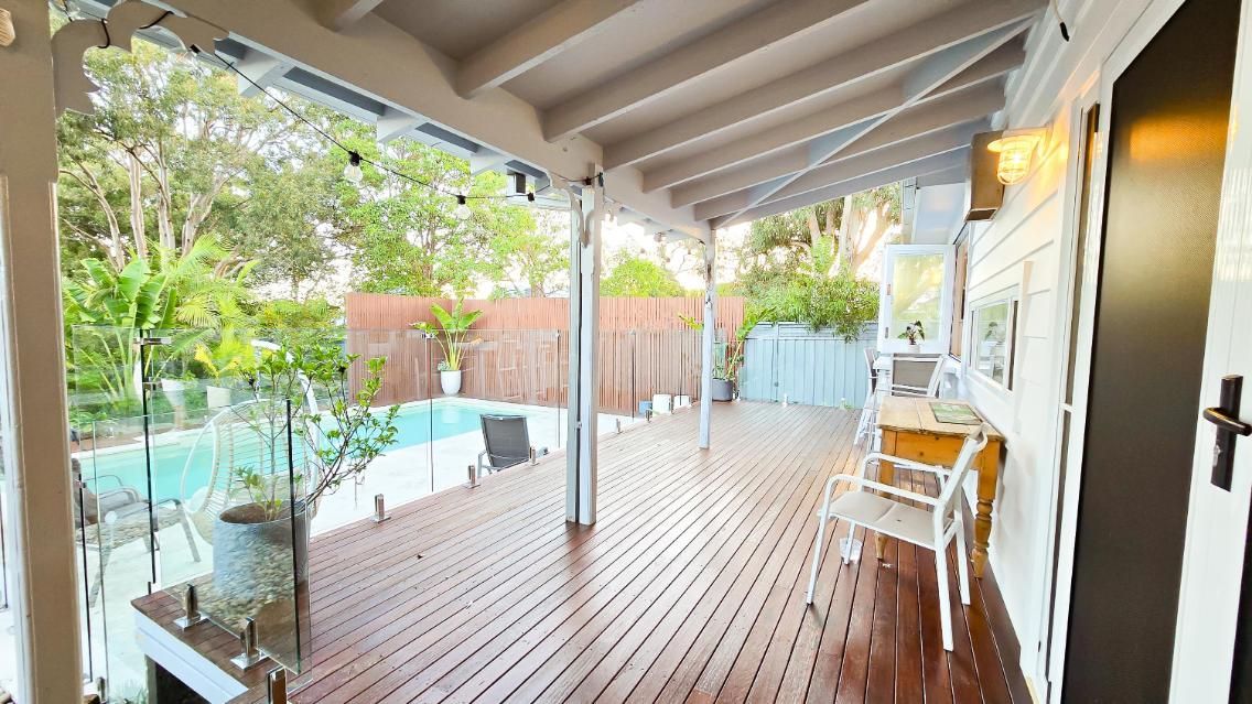 A Large Wooden Deck With A Swimming Pool In The Background — APEX Painting & Maintenance In Primbee, NSW