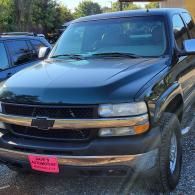 Black Chevrolet SUV parked outdoors with a pink front plate holder