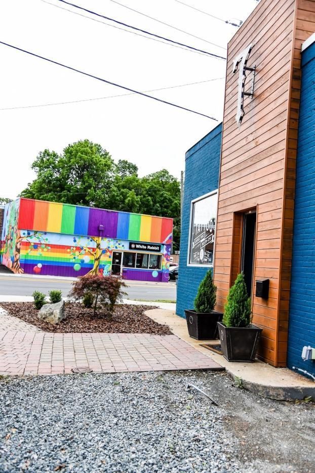 A building with a blue brick facade and wooden entrance next to a street with a colorful, rainbow-painted storefront.