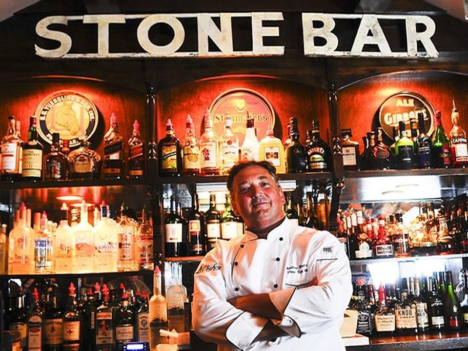 A man is standing in front of a stone bar 