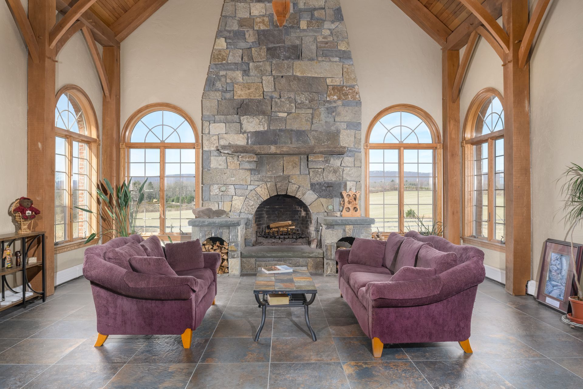 A living room with purple furniture and a stone fireplace at Chestnuthill Countryside Manor
