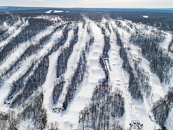 An aerial view of a ski resort surrounded by snow covered trees.