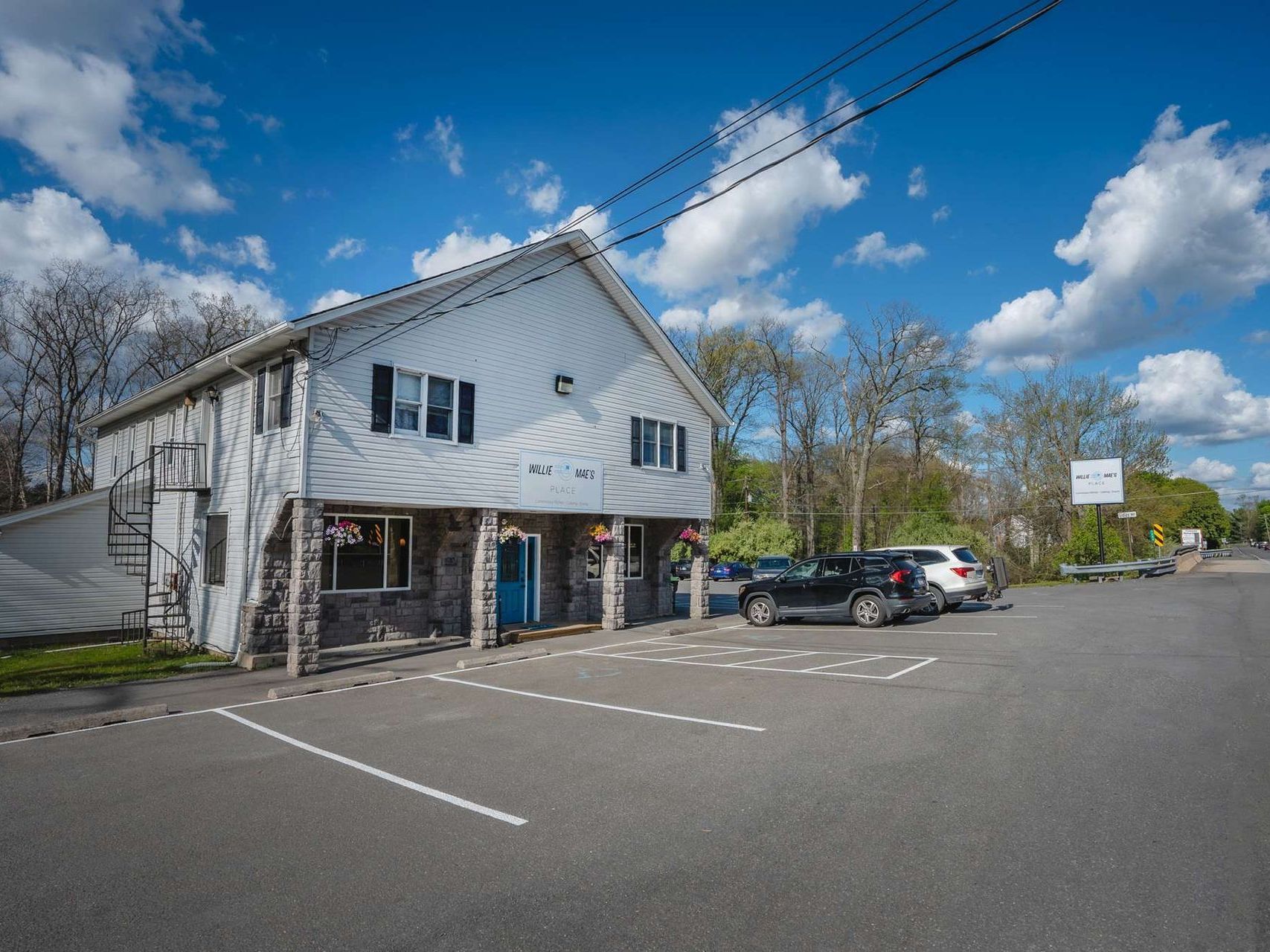 A white building with cars parked in front of it on a sunny day.