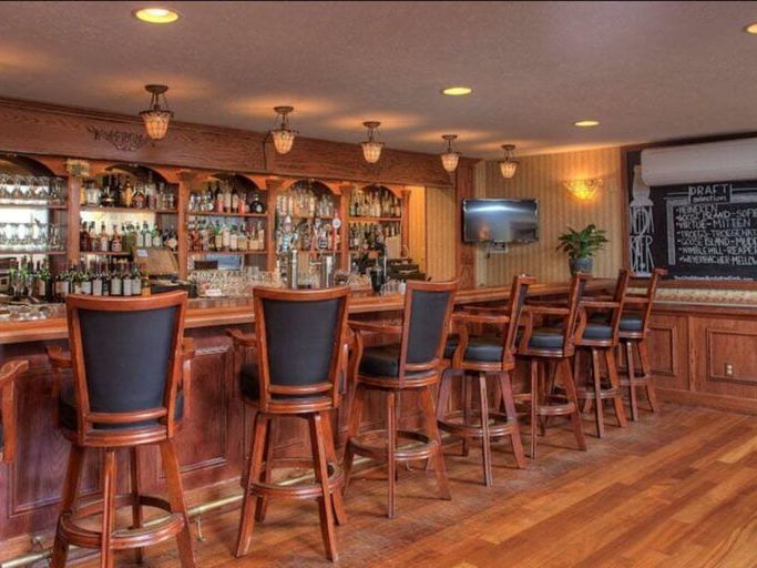A row of bar stools are lined up in front of a bar 