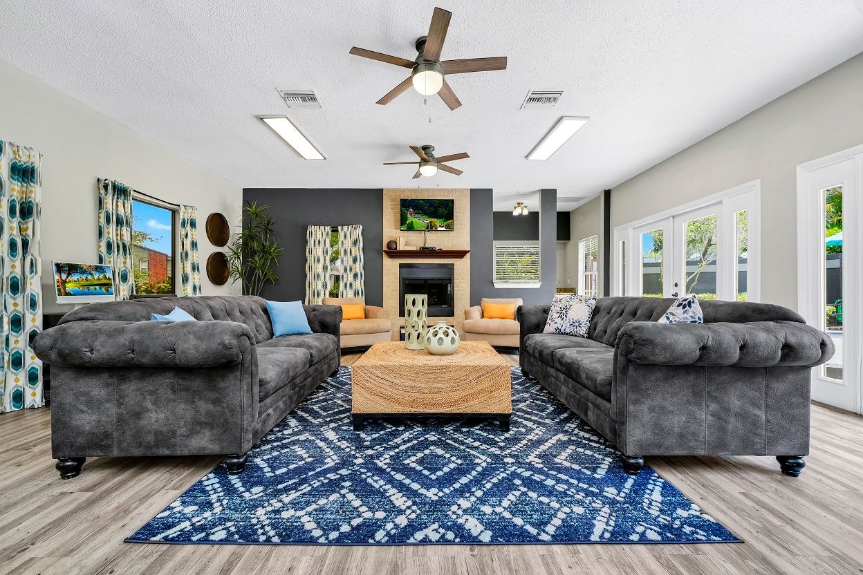 Cozy living room with two gray couches, blue rug, coffee table, and fireplace at The Glades in Altamonte Springs, FL.