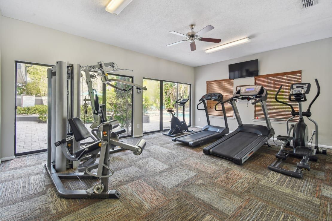 Gym with exercise equipment, including treadmills, elliptical, and weight machines.
