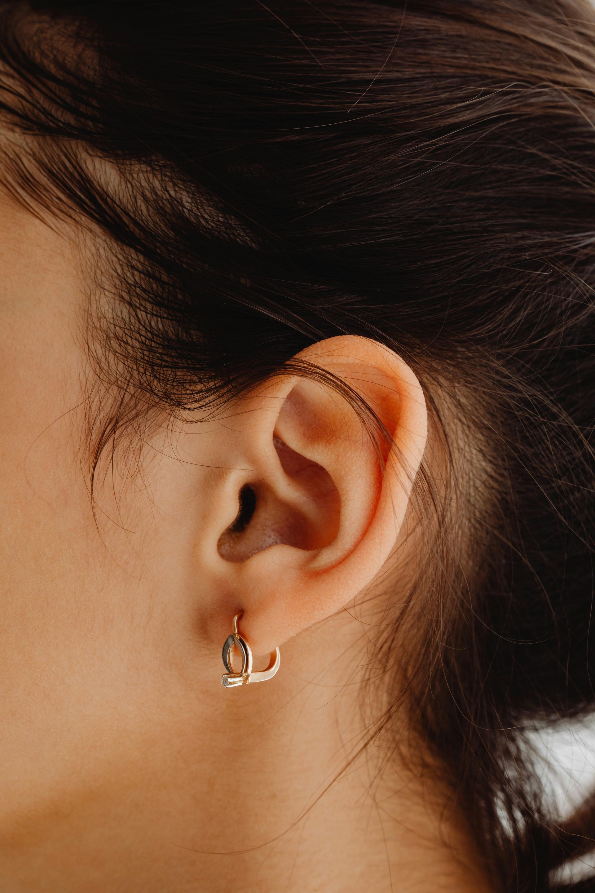 Close-up of a person's ear wearing a gold hoop earring.