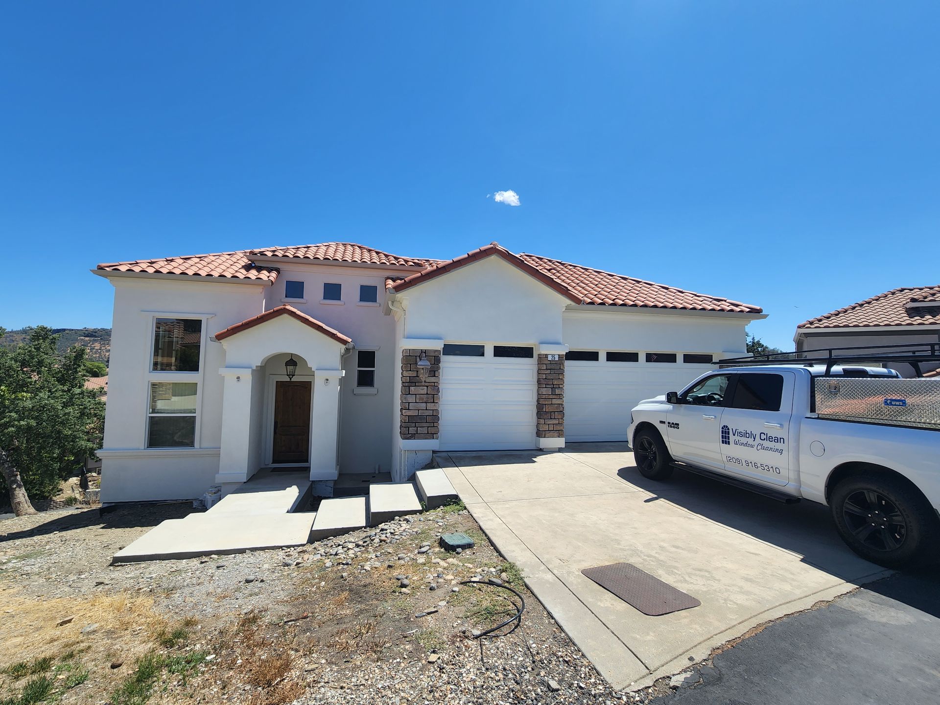 A white truck is parked in front of a white house.