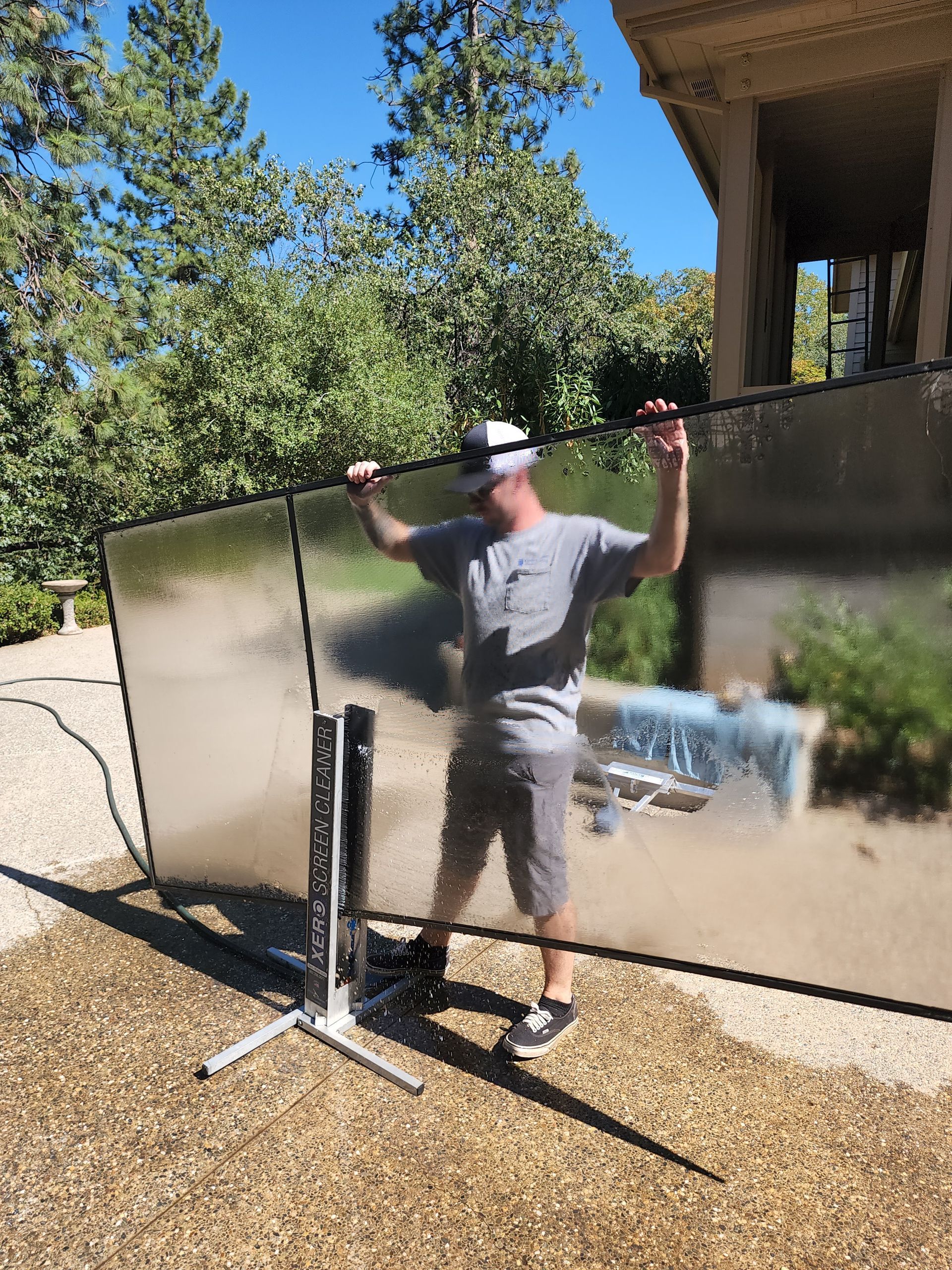 A man is holding a large piece of glass in front of a house.