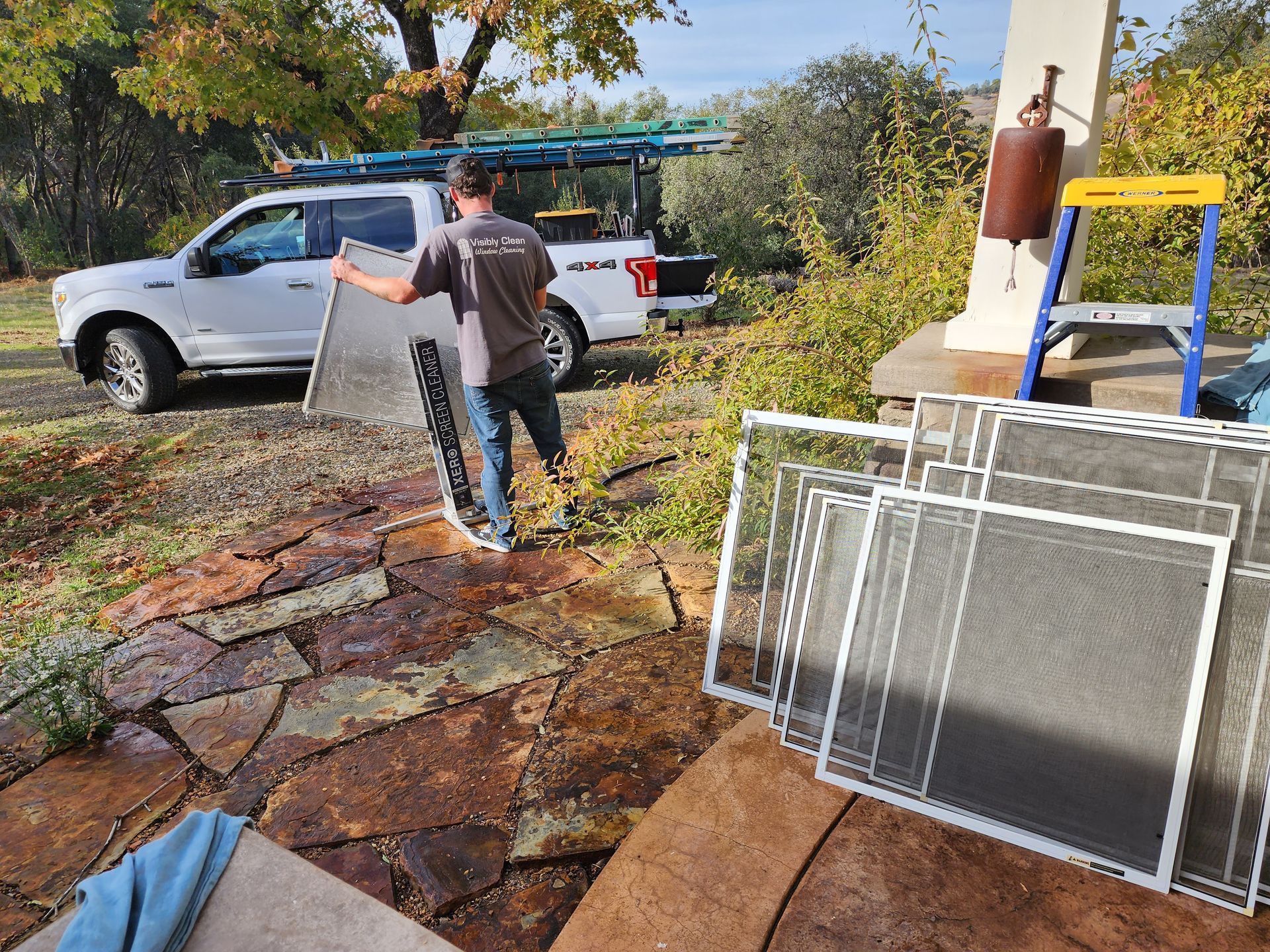 A man is carrying a screen door in front of a truck.
