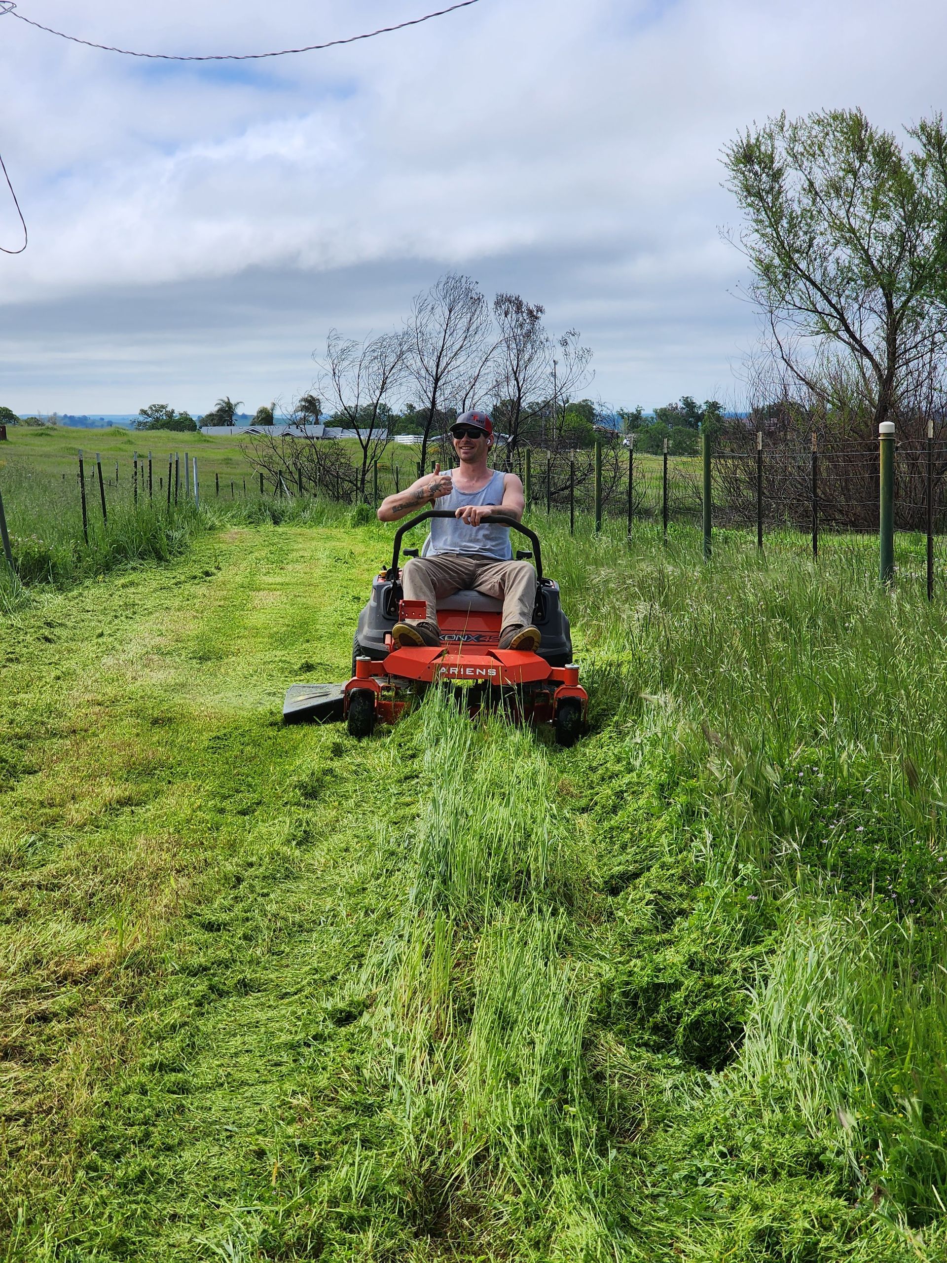 A man is riding a lawn mower through a grassy field.