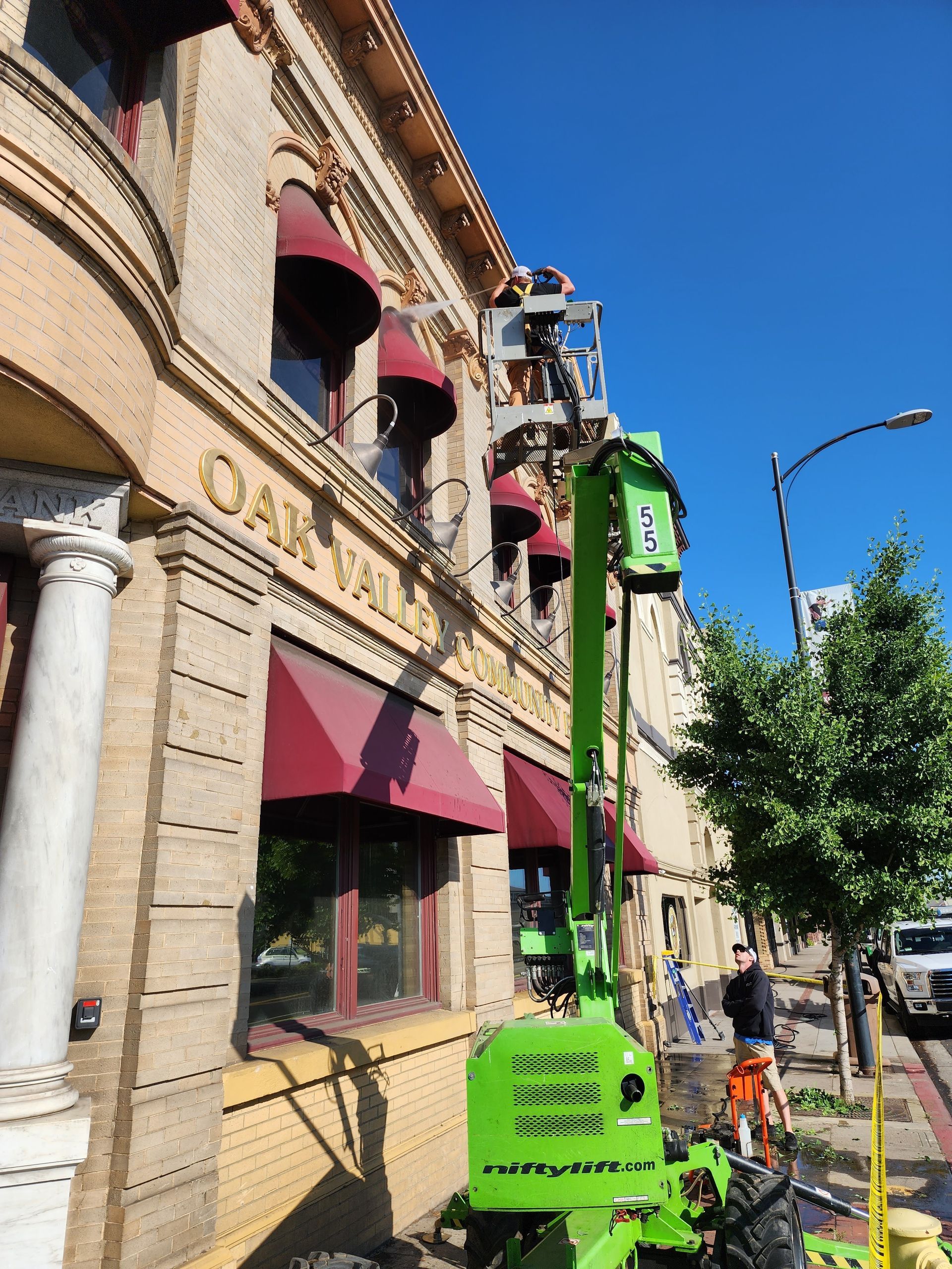 A green crane is on the side of a building that says oak valley