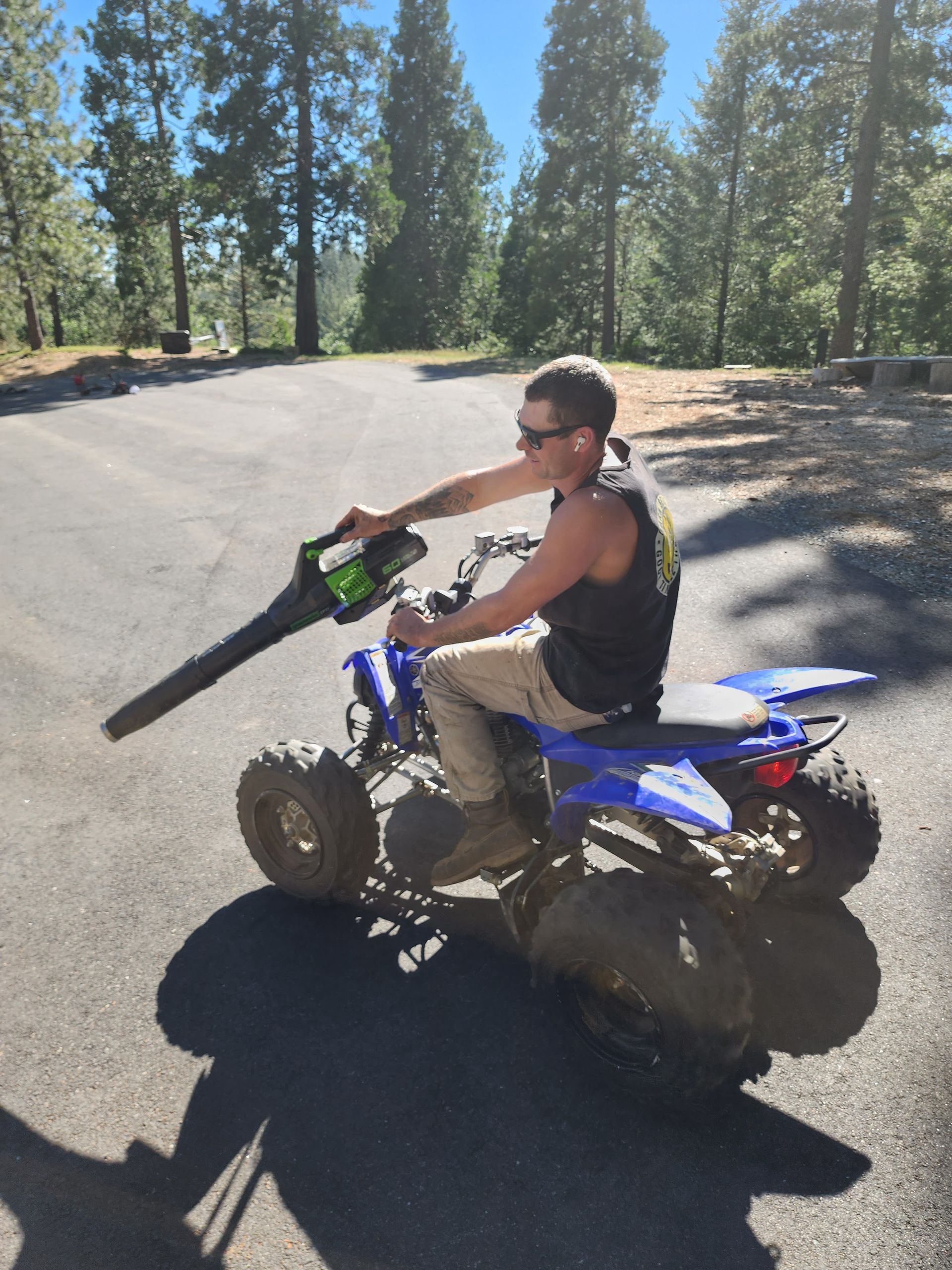 A man is riding an atv with a blower attached to it