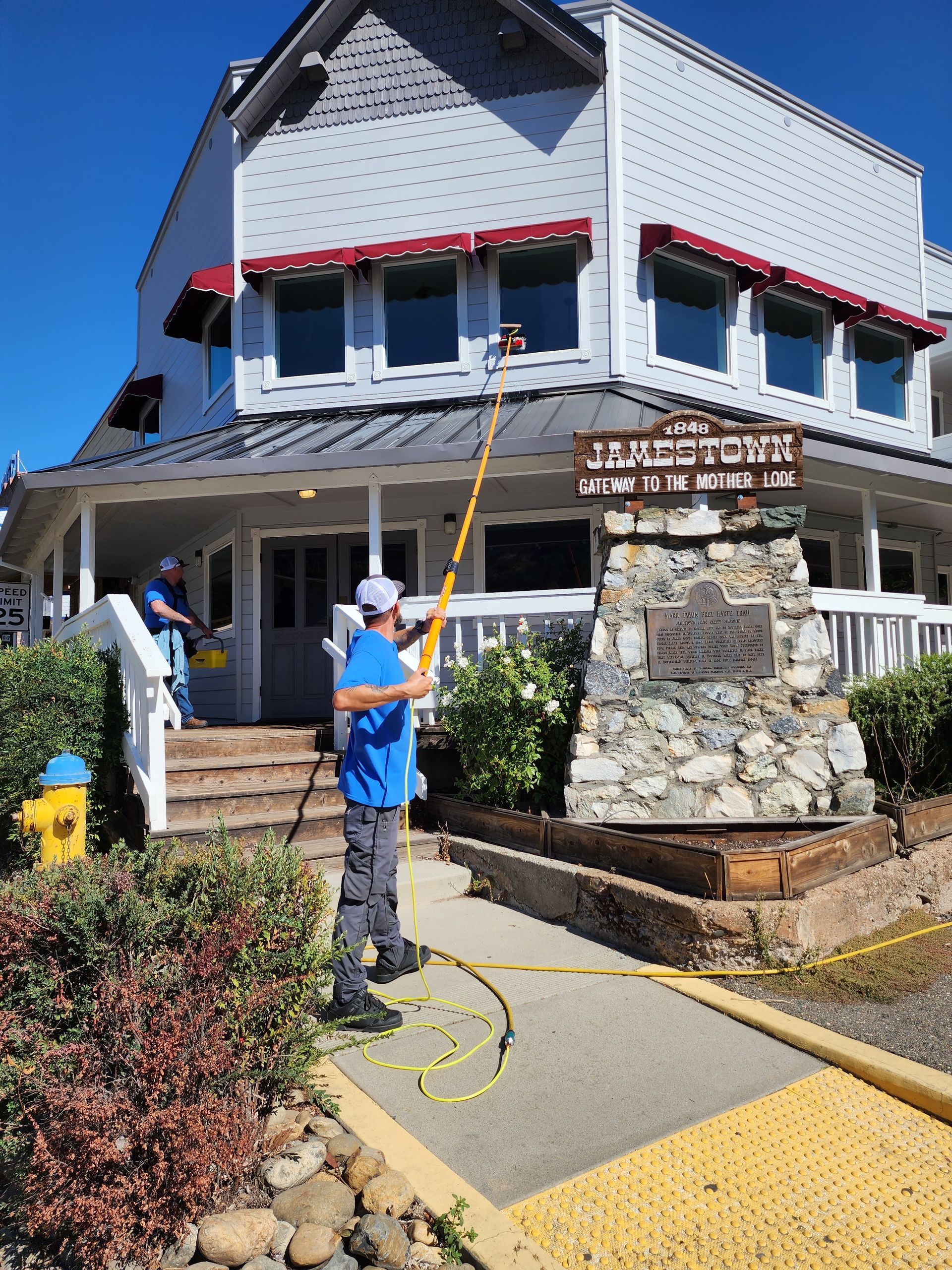 A man is cleaning the outside of a building with a hose.