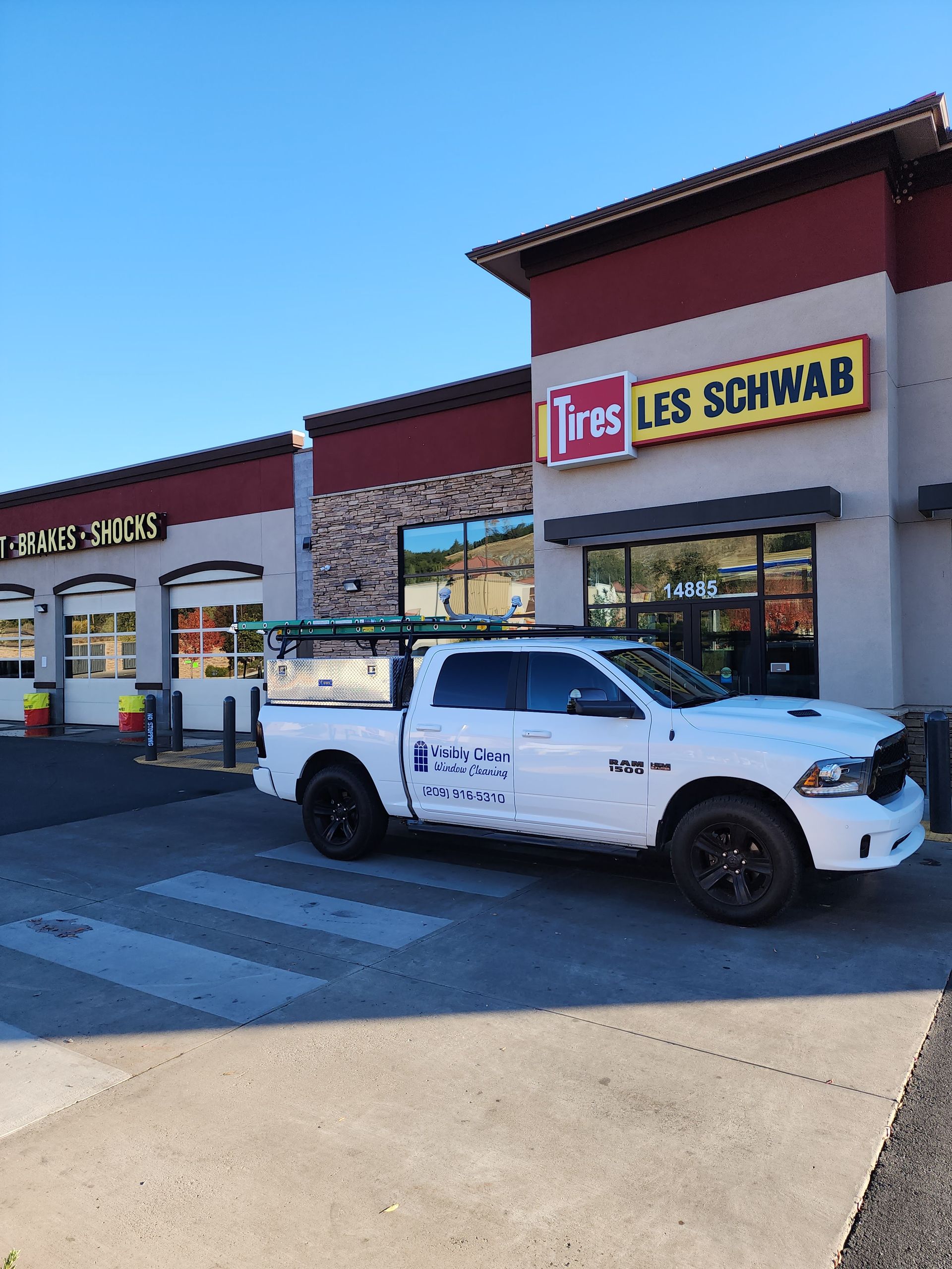 A white truck is parked in front of a les schwab store.