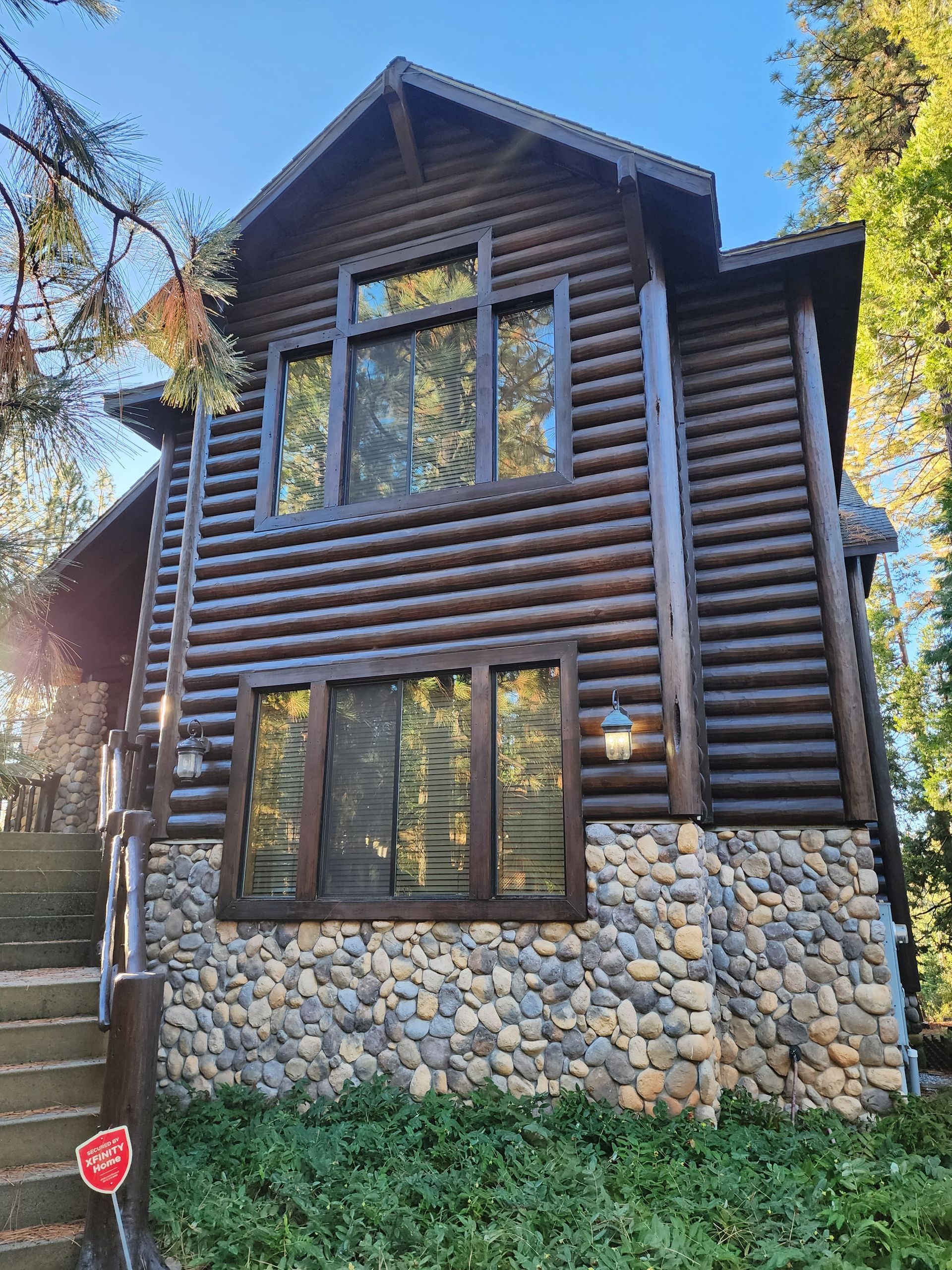 A large log cabin with a stone wall and stairs.
