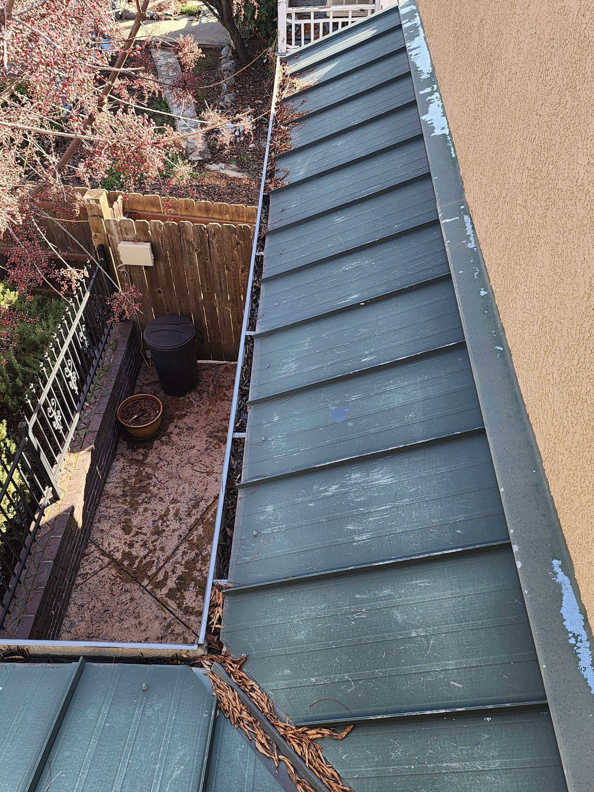 A gutter on the side of a building with leaves on it.