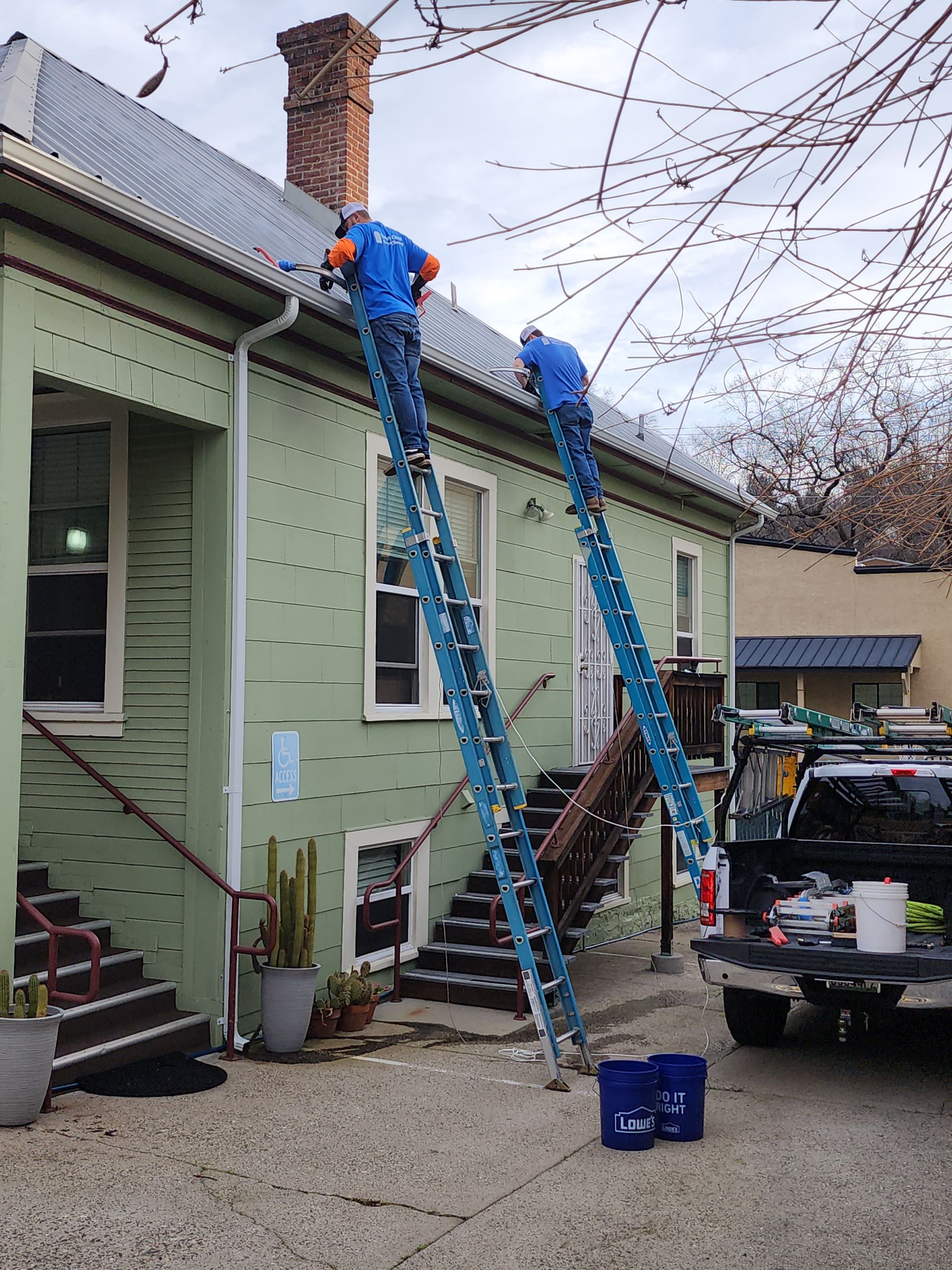 Two men are working on the roof of a green building.