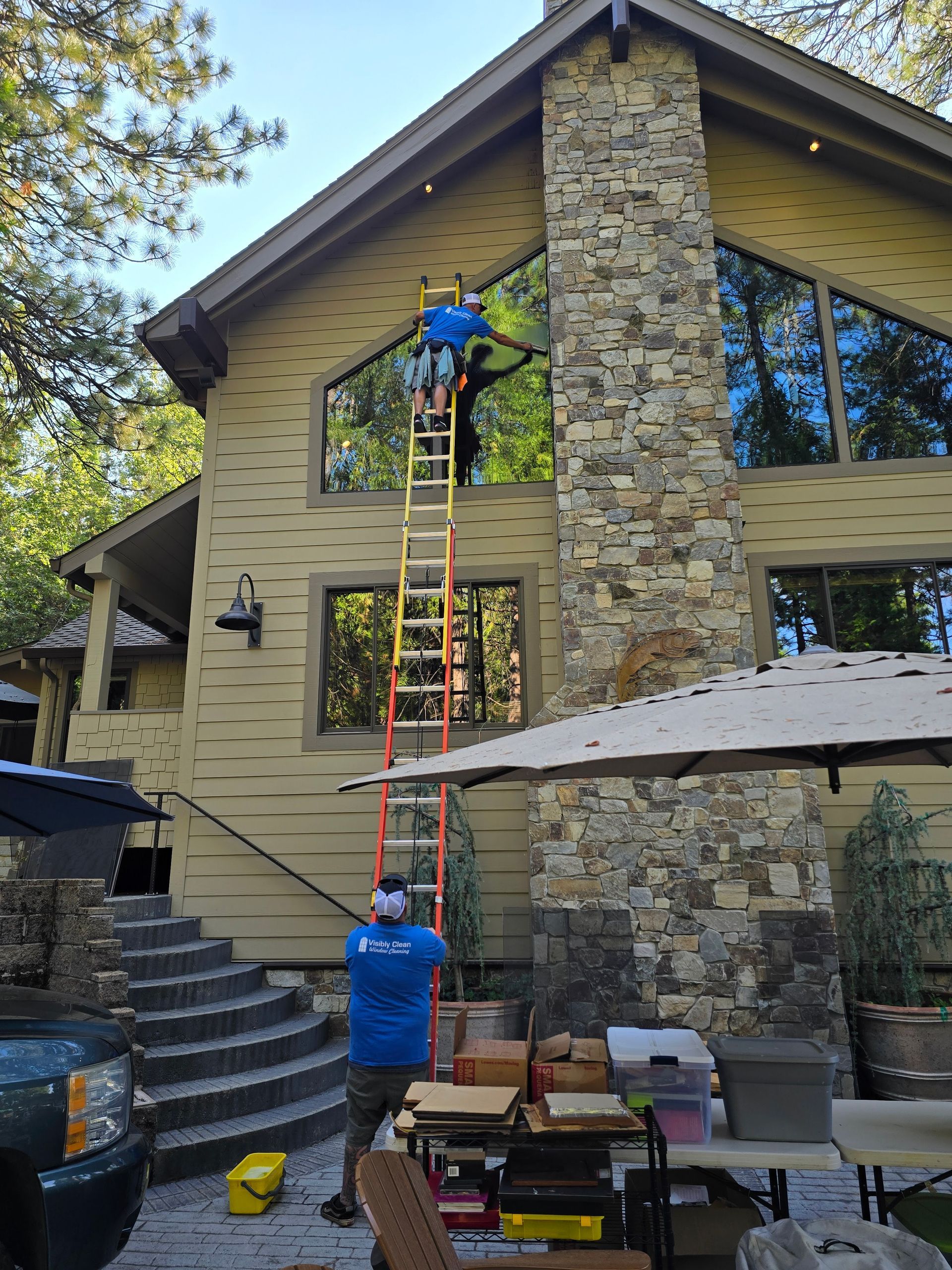 A man is standing on a ladder in front of a large house.