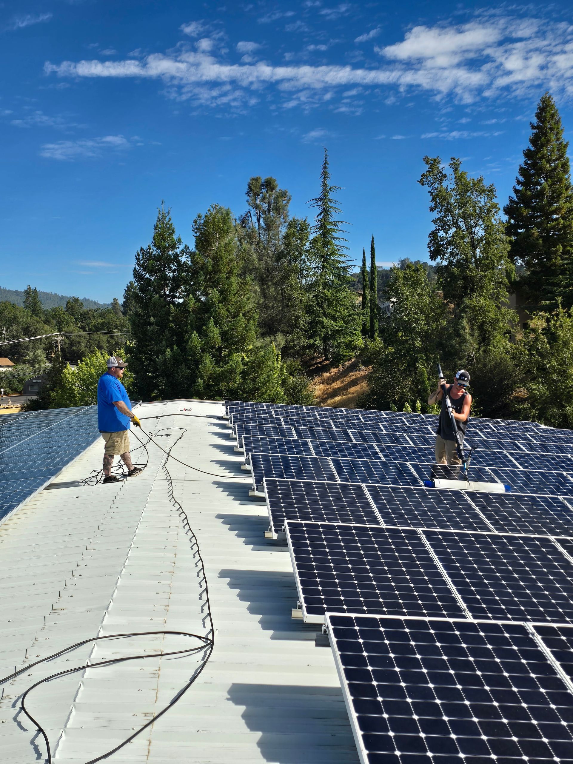 Two men are working on a roof with solar panels.