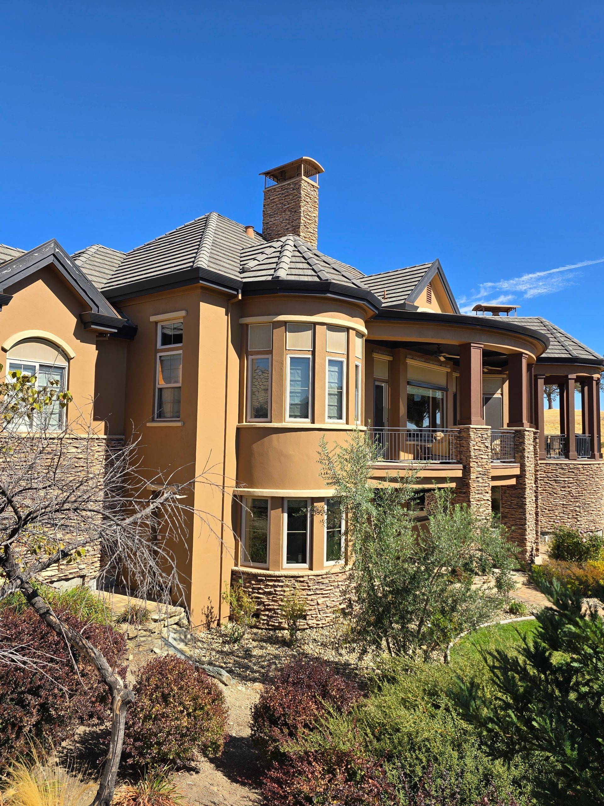 A large house with a lot of windows is surrounded by trees and bushes.