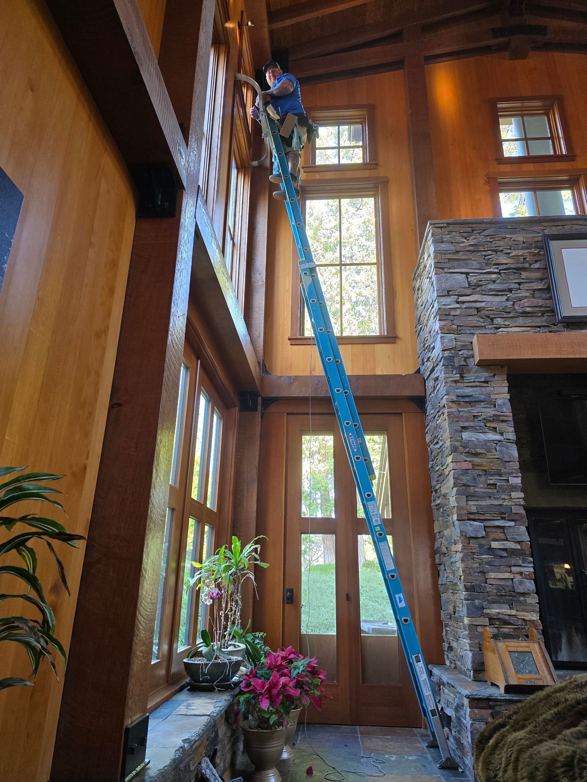 A man is standing on a ladder in a living room.