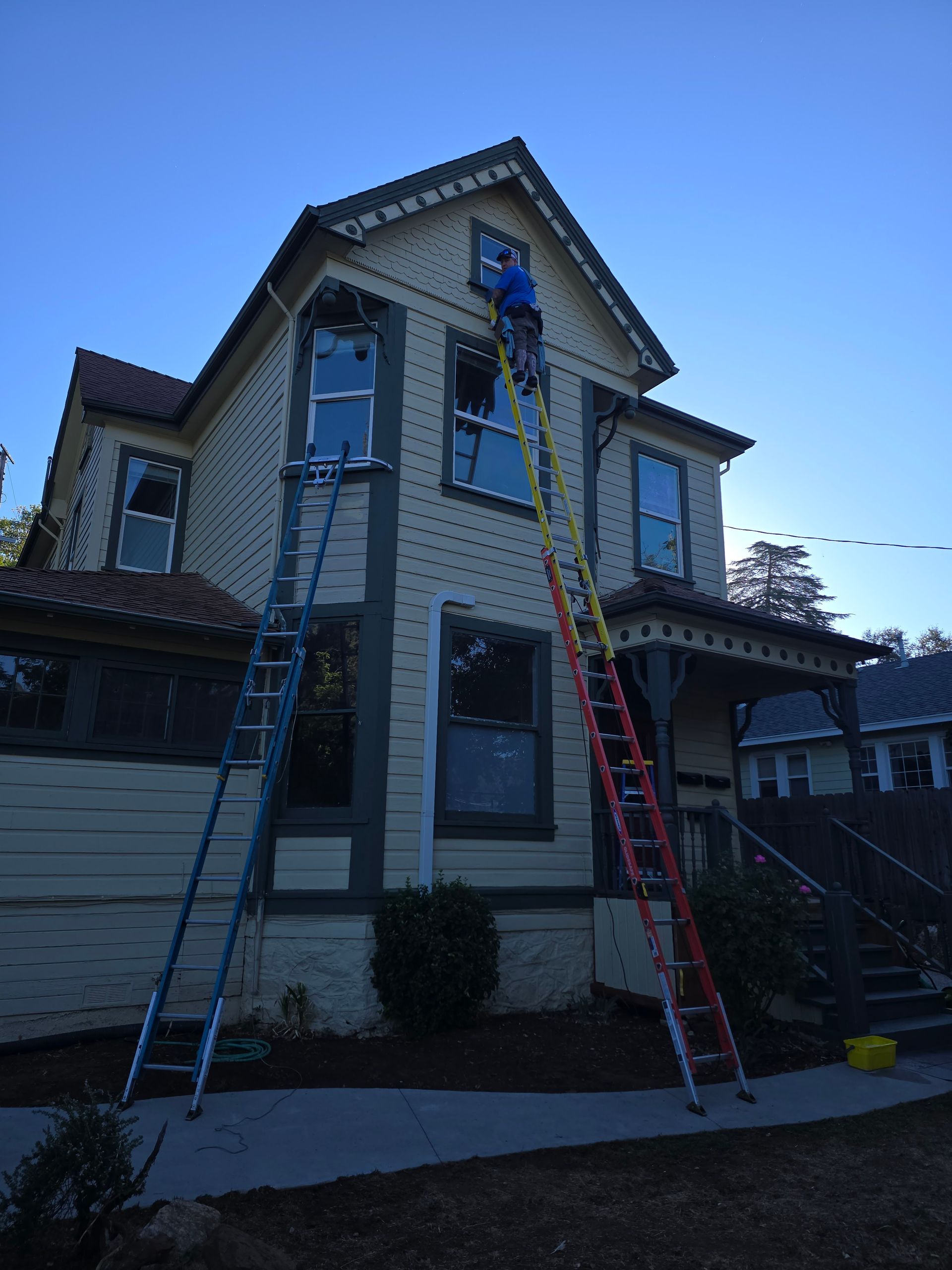 A man is standing on a ladder in front of a house
