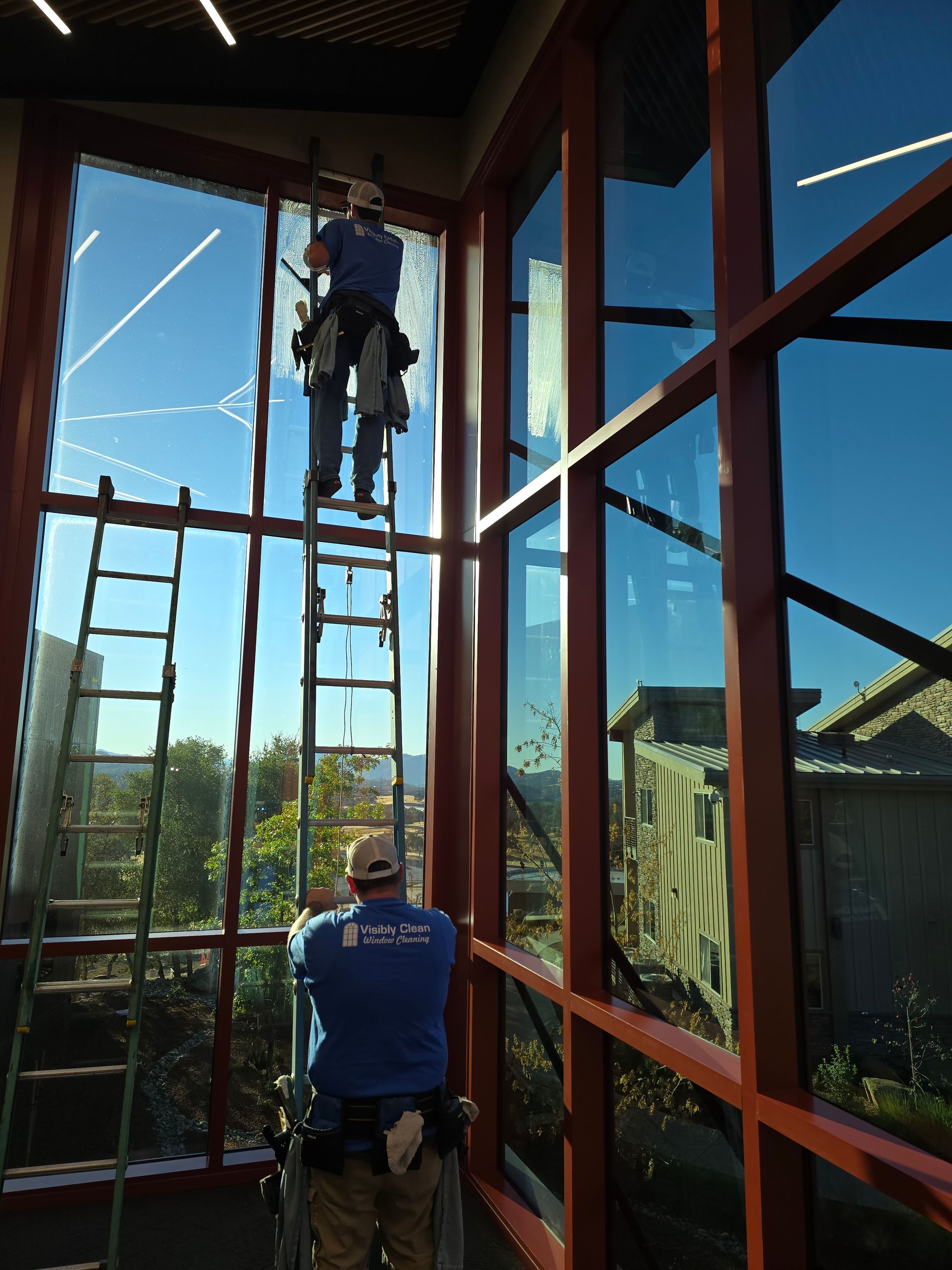 A man on a ladder cleaning a large window