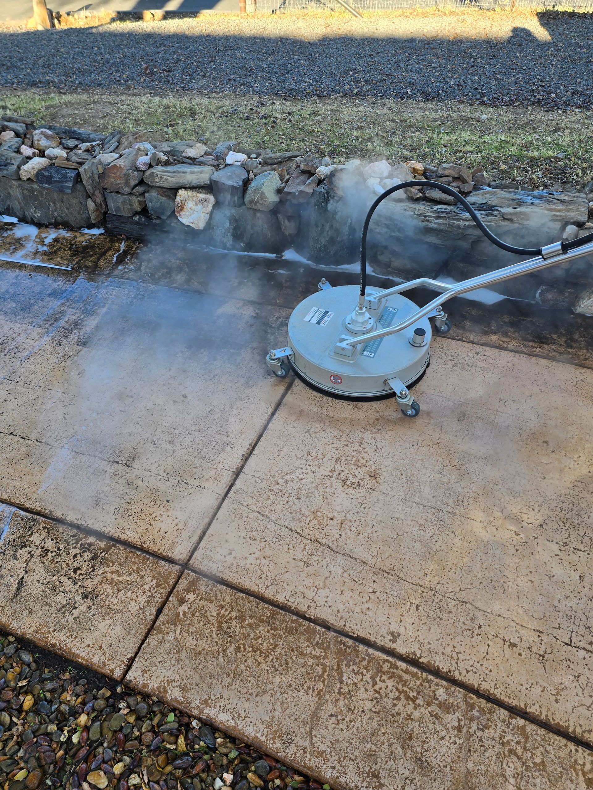 A pressure washer is cleaning a concrete sidewalk.