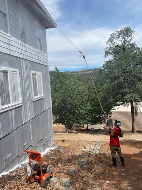 A man is spraying a house with a hose.