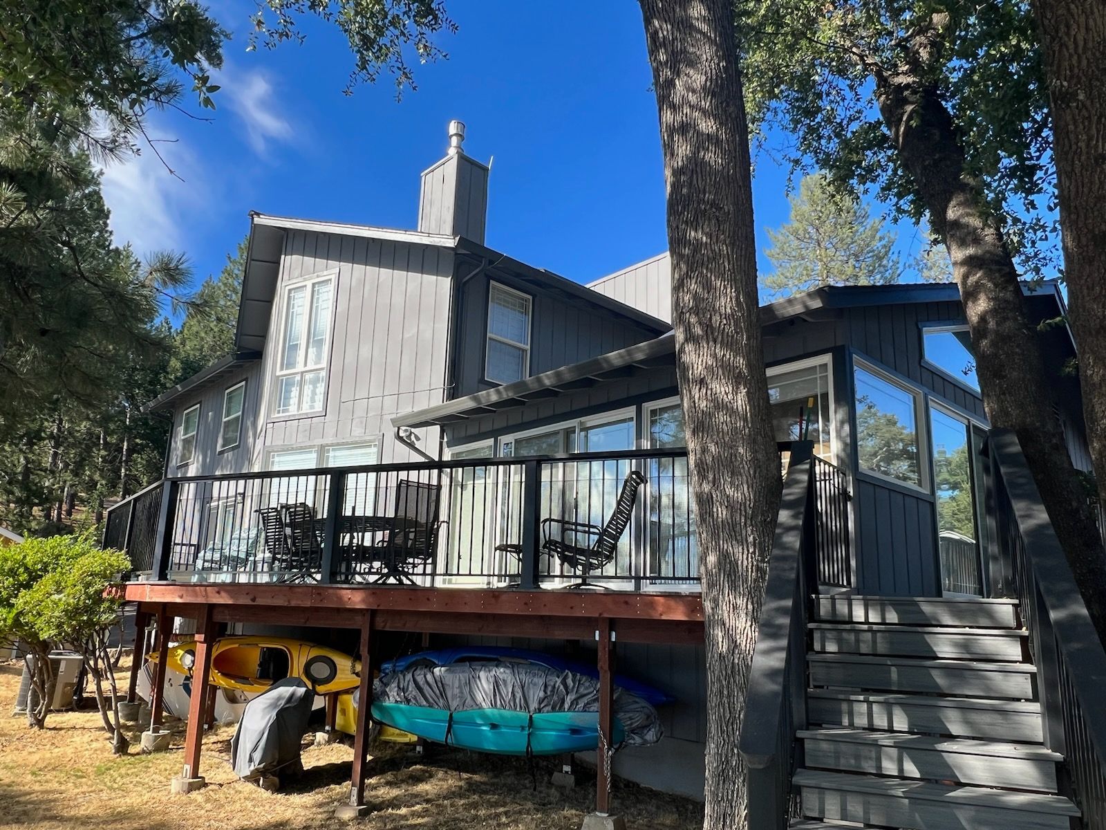 A large house with a large deck and kayaks underneath it.