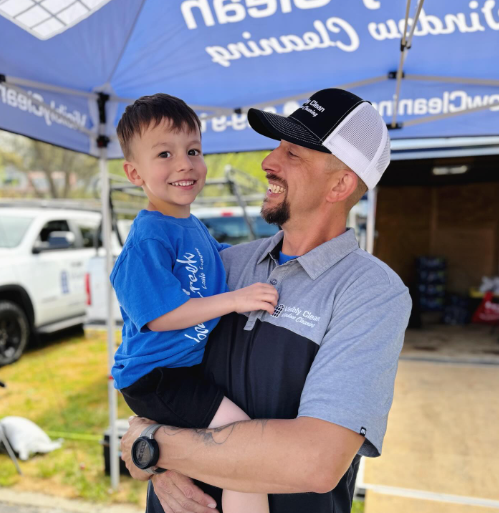A man is holding a little boy in his arms in front of an umbrella that says primal