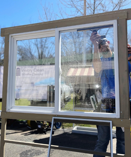 A man is cleaning a window with a squeegee.