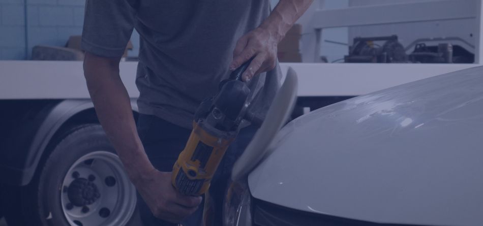 Um homem está polindo um carro branco com uma lixadeira.