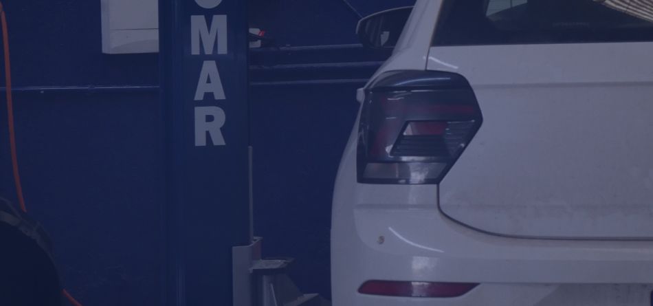 Um carro branco está parado em um elevador em uma garagem.