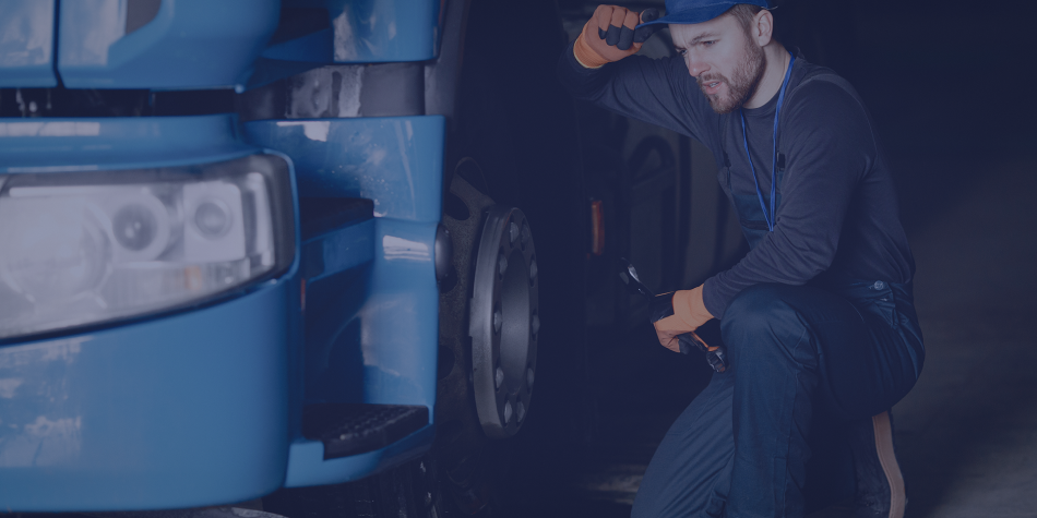 Um homem está trabalhando em um caminhão azul em uma garagem à noite.