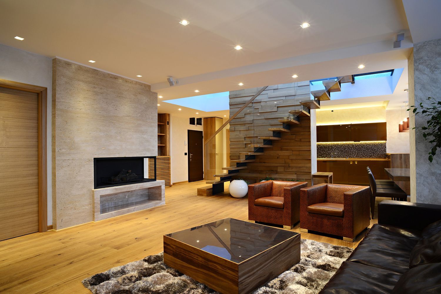 Living room with wooden floors, fireplace, and stairs. Leather armchairs, coffee table on shag rug. Living room with wooden floors, fireplace, and stairs. Leather armchairs, coffee table on shag rug.