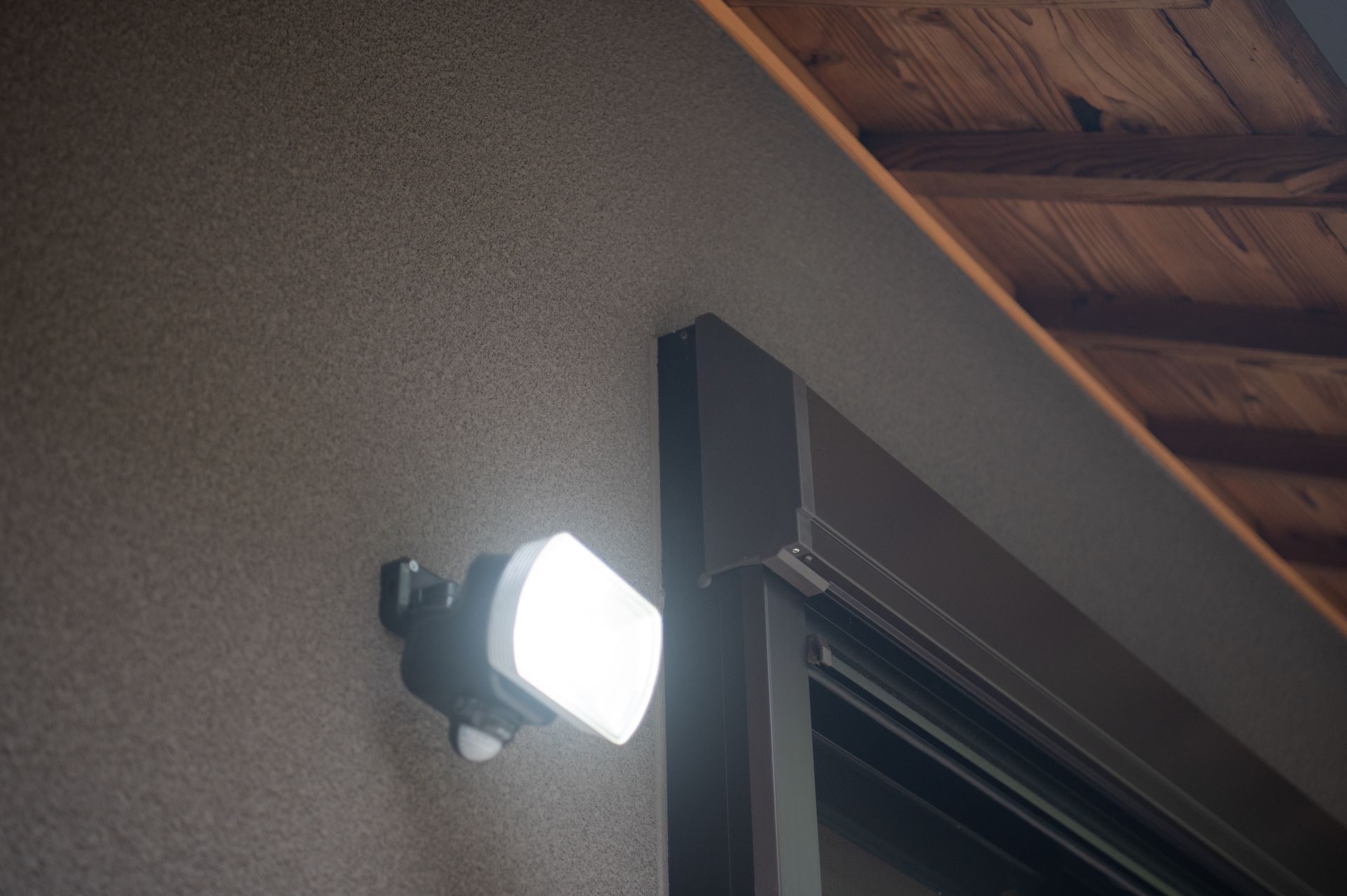 Illuminated LED motion-sensor security light mounted on an exterior wall at dusk Illuminated LED motion-sensor security light mounted on an exterior wall at dusk