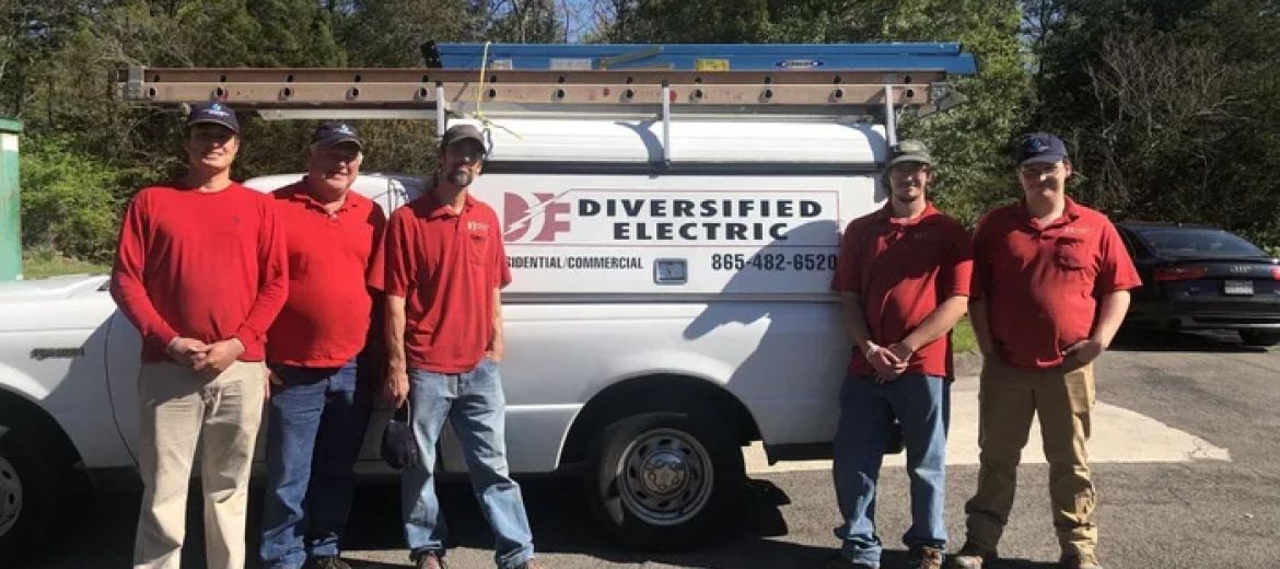 Six men in red shirts and caps stand in front of a white truck that says 