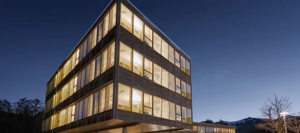 Modern building at night with lit windows against a dark blue sky.