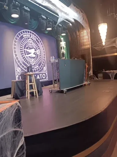 Stage set with a dark stage, lit by spotlights, with a logo on the back, and Halloween decorations.