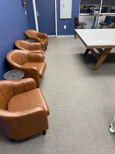 Brown armchairs line a blue wall in a room with a large table and gray carpet.