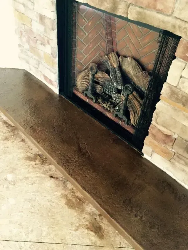 Fireplace with stacked stone surround, brick interior, and wood-look hearth.