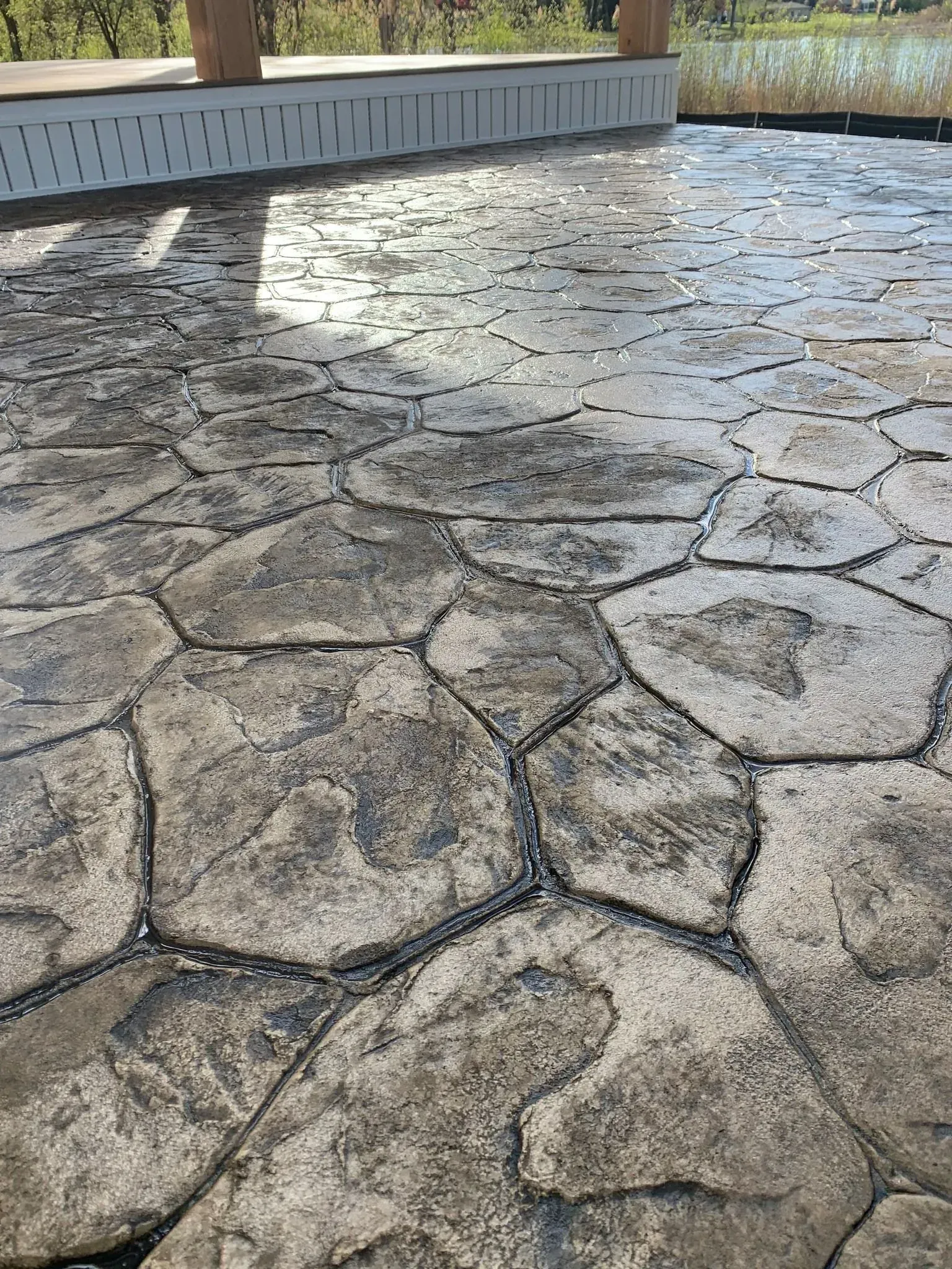 Stamped concrete patio with a stone pattern, near a lake.