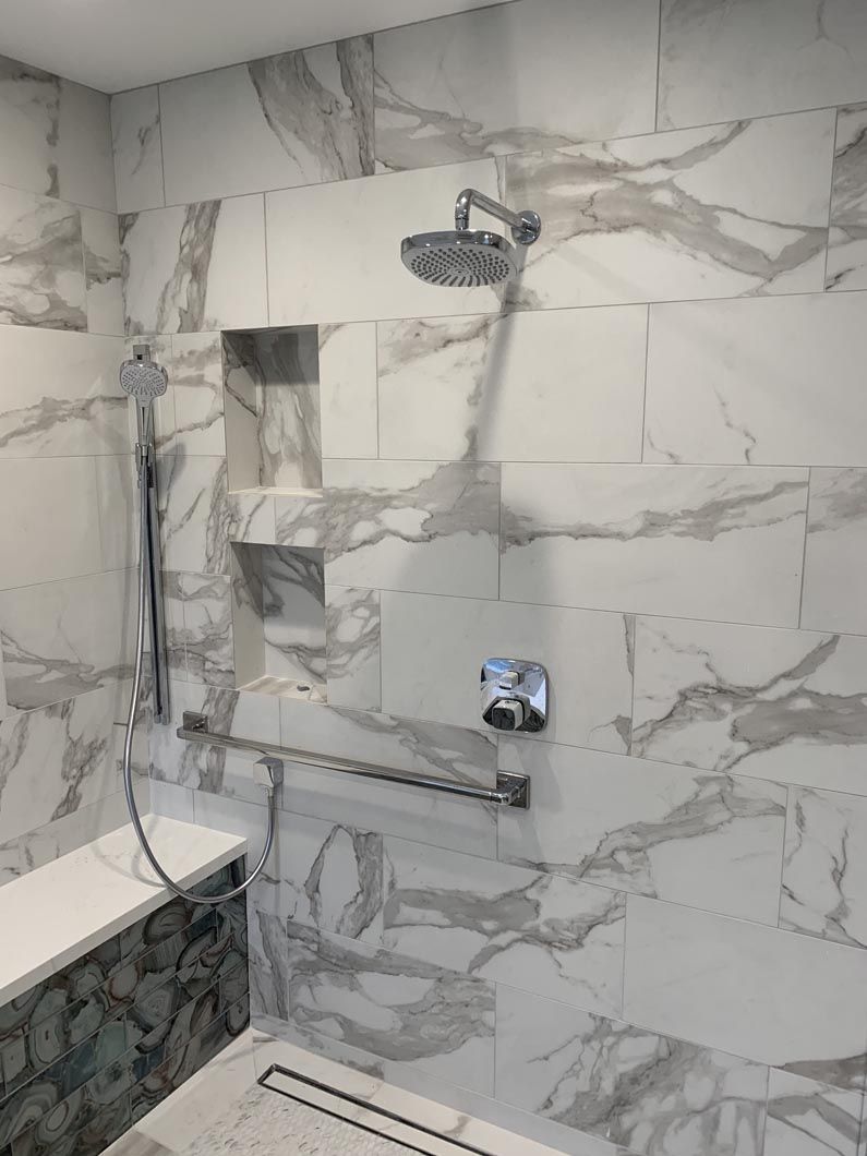 A bathroom with marble tiles and a shower head.