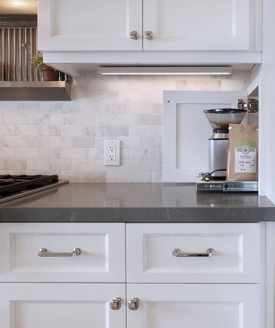 A kitchen with white cabinets and a coffee grinder on the counter.
