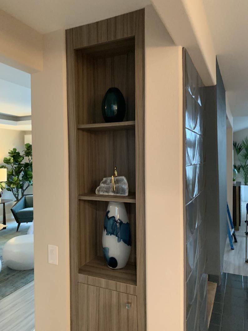 A vase is sitting on a wooden shelf in a living room.