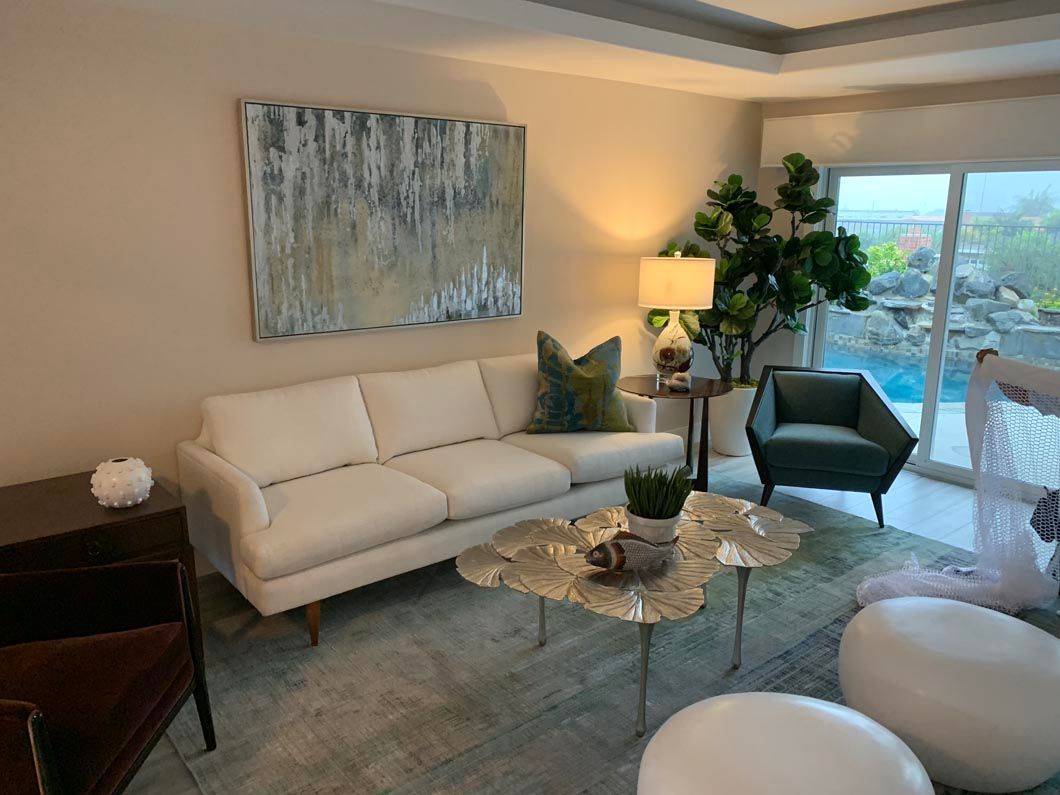 A living room with a couch , chairs , coffee table and a painting on the wall.