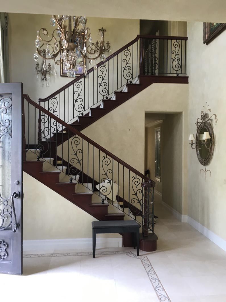 A staircase with a wrought iron railing in a hallway